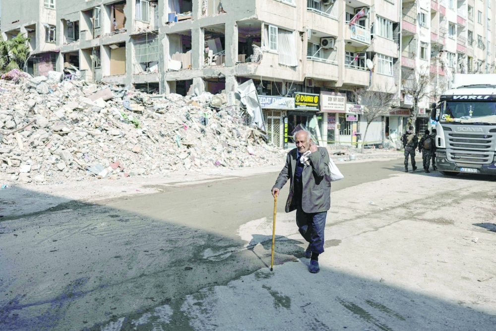 A man walks past collapsed buildings in Antakya, southern Turkiye. — AFP