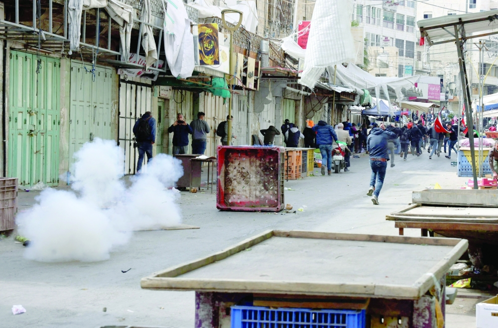 Activists run from tear gas fired by Israeli security forces during a demonstration against the presence of Israeli settlers in Hebron in the centre of the West Bank town. -  AFP


