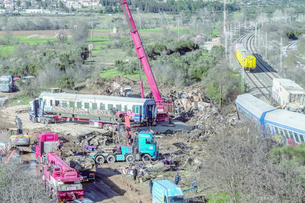 Workers remove parts of the wrecked train carriages at the site of a crash near Larissa, Greece.
