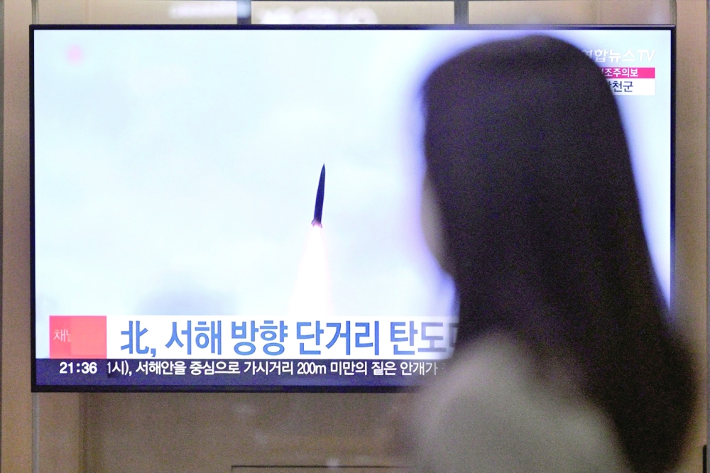 A woman walks past a television showing a news broadcast with file footage of a North Korean missile test at a railway station in Seoul. — AFP 