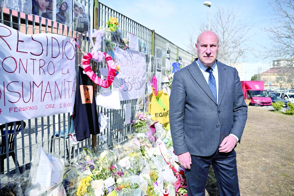Crotone's mayor Vincenzo Voce poses by candels and flowers outside the Crotone Palasport where lies for identification the migrants.— AFP 