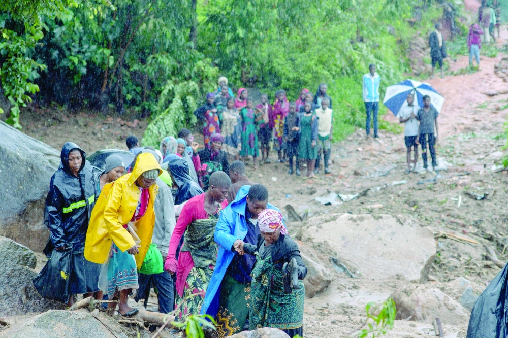 People walk up a hill in Blantyre on Tuesday, following cyclone Freddy's landfall. - AFP