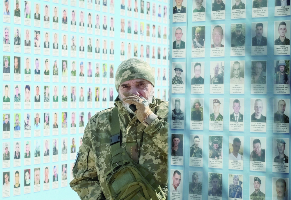 A serviceman visits the Wall of Remembrance to pay tribute to killed Ukrainian servicemen during a commemorative ceremony to mark the Volunteer Day honouring fighters, in Kyiv, Ukraine, on Tuesday. - Reuters