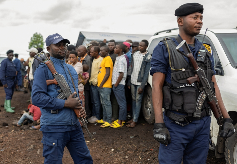 Congolese police officers stand guard near internally displaced people gathered during the visit of a delegation of the UN Security Council at the Bushagara site. — Reuters