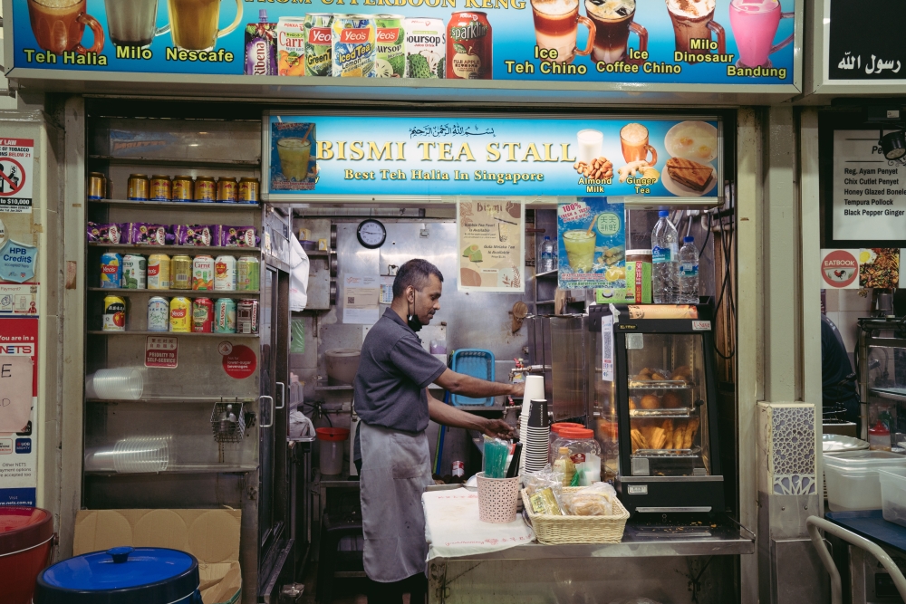 A stall owner preparing drinks at Amoy Street Food Center in Singapore, March 2, 2023. (Amrita Chandradas/The New York Times)