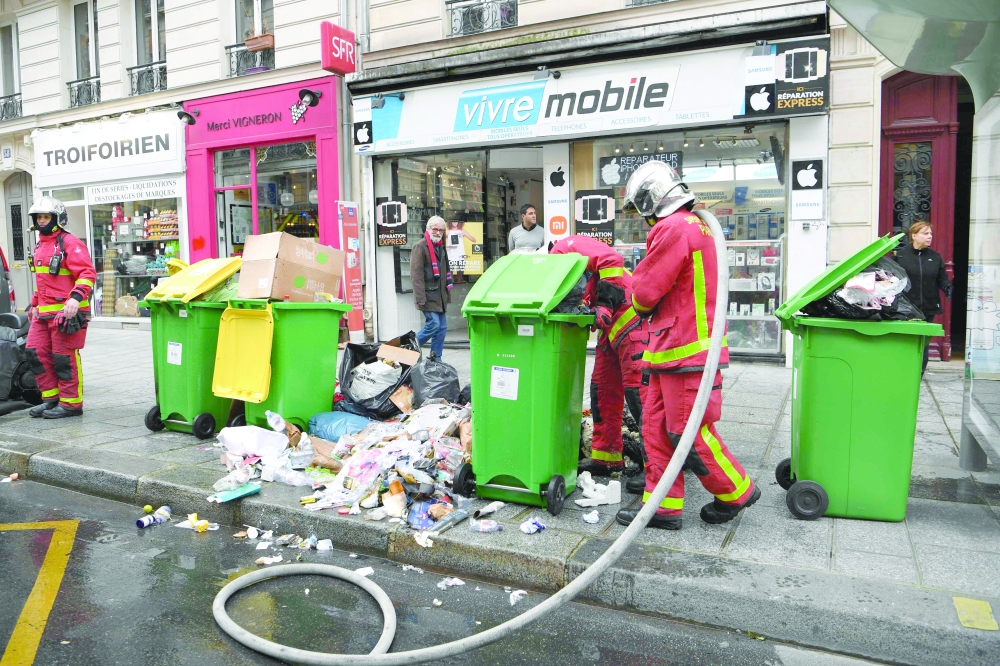 Firefighters intervene to stop a fire to start in full waste bins as rubbish collectors strike against pension reforms, leaving many streets in the capital piled with stinking waste in Paris. - AFP


