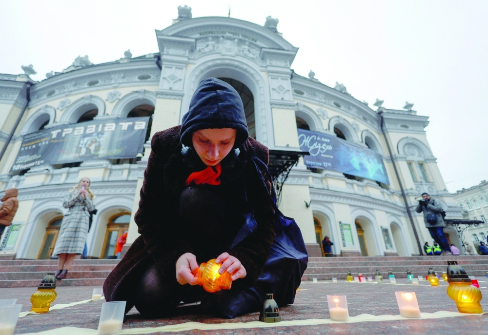 A woman lights a candle during a commemorative rally for people killed a year ago inside building of the Mariupol's Drama Theatre by Russian air strike, amid a siege on the city during Russia's invasion, in front of the Opera Theatre in Kyiv. - Reuters 
