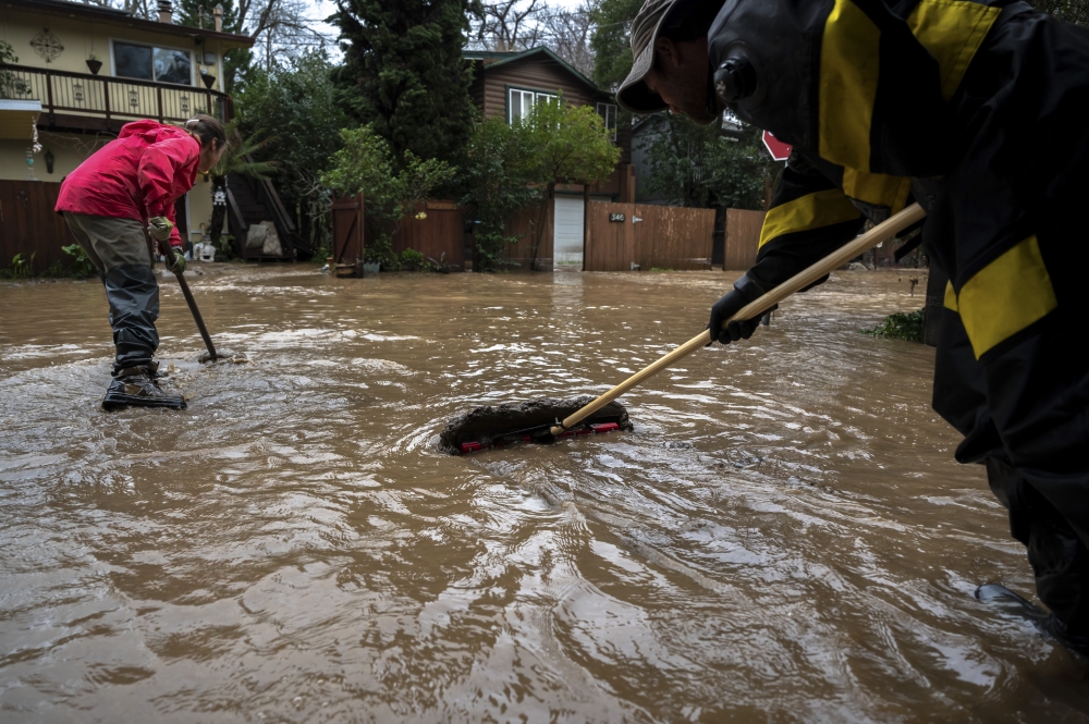 Residents move mud away from their home amid flooding caused by storms in Felton Grove, Calif., Jan. 14, 2023. (Mike Kai Chen/The New York Times) 