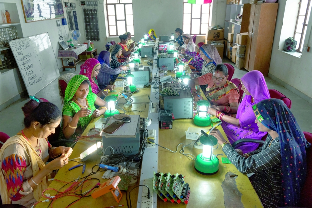 Women from villages near Tilonia, India learn how to make solar lamps at the Barefoot College.
