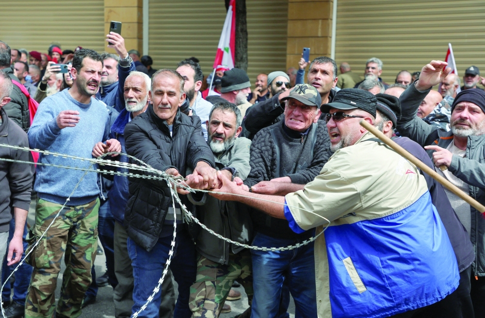 Retired Lebanese soldiers pull a barbed wire during a protest over the deteriorating economic situation, at Riad al-Solh square in Beirut. — Reuters