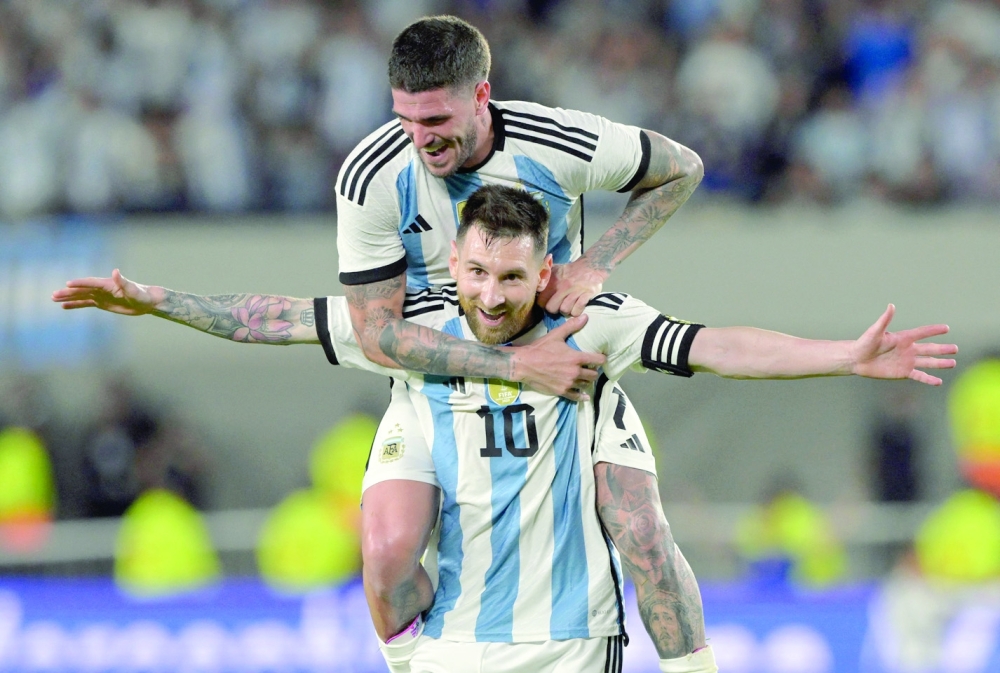 Argentina's forward Lionel Messi celebrates with midfielder Rodrigo De Paul (top) after scoring a goal during the friendly football match between Argentina and Panama at the Monumental stadium in Buenos Aires, on March 23, 2023. (Photo by JUAN MABROMATA / AFP)