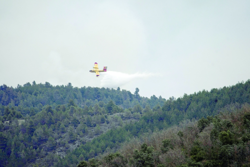 A military plane drops water on a wildfire in San Agustin, Spain. - Reuters
