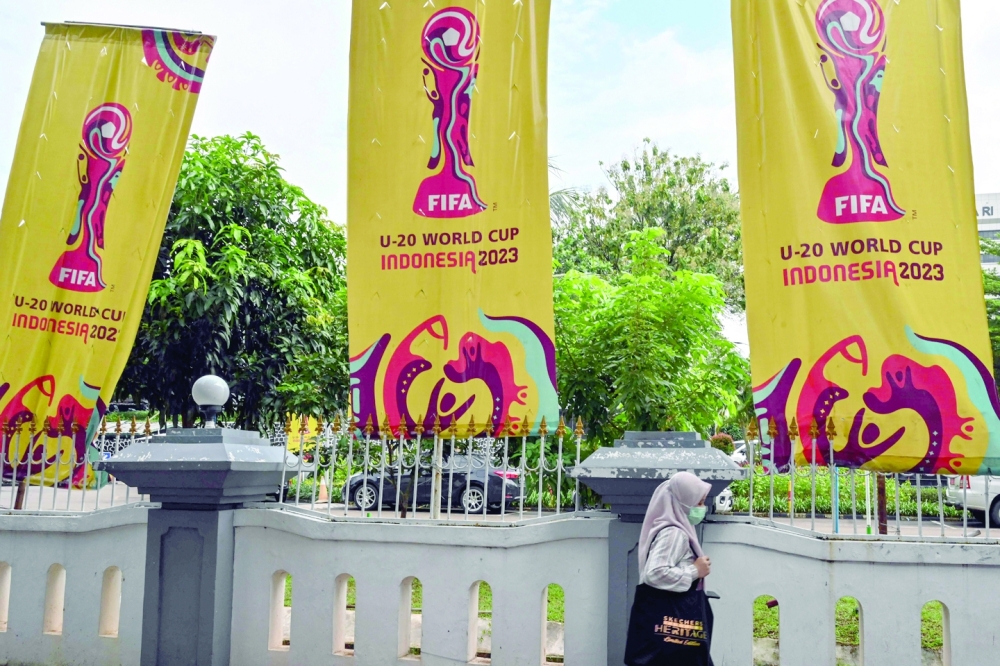 A woman walks past banners for the Indonesia 2023 FIFA Under-20 World Cup football tournament in Jakarta on March 30, 2023. FIFA announced on March 29 it had removed Indonesia as hosts of this year's under-20 World Cup amid political turmoil over Israel's participation. (Photo by ADEK BERRY / AFP)

