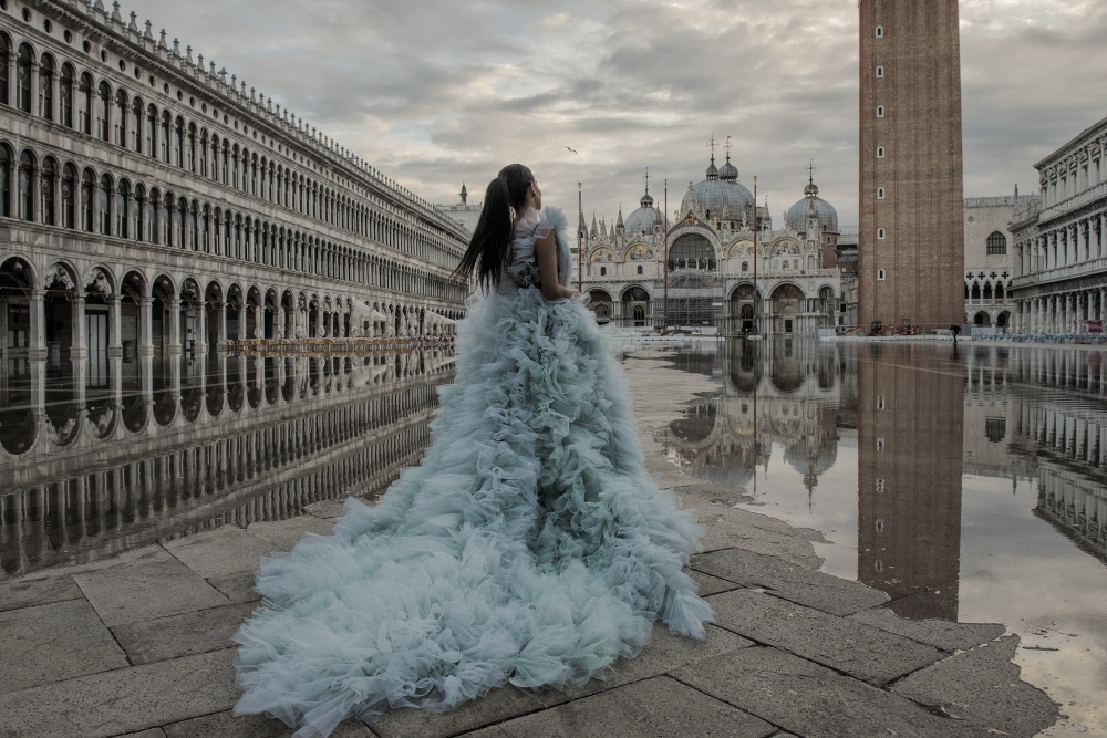 A woman stands near flood water on St. Mark's Square in Venice, Italy on Nov. 20, 2022. (Laetitia Vancon/The New York Times)