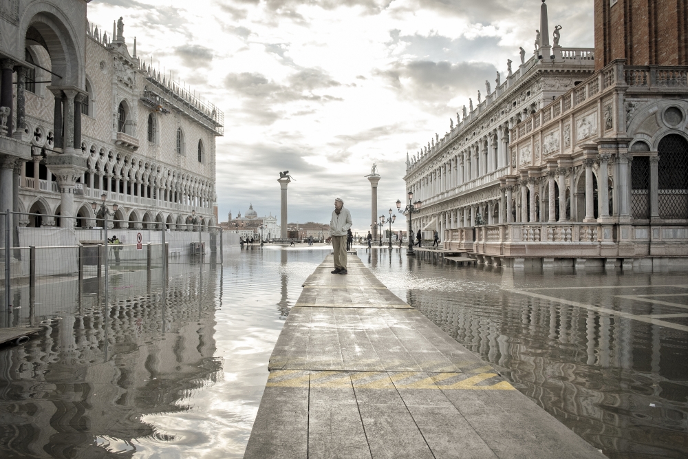 A tourist navigates flood water on St. Mark's Square in Venice, Italy on Nov. 20, 2022. (Laetitia Vancon/The New York Times)