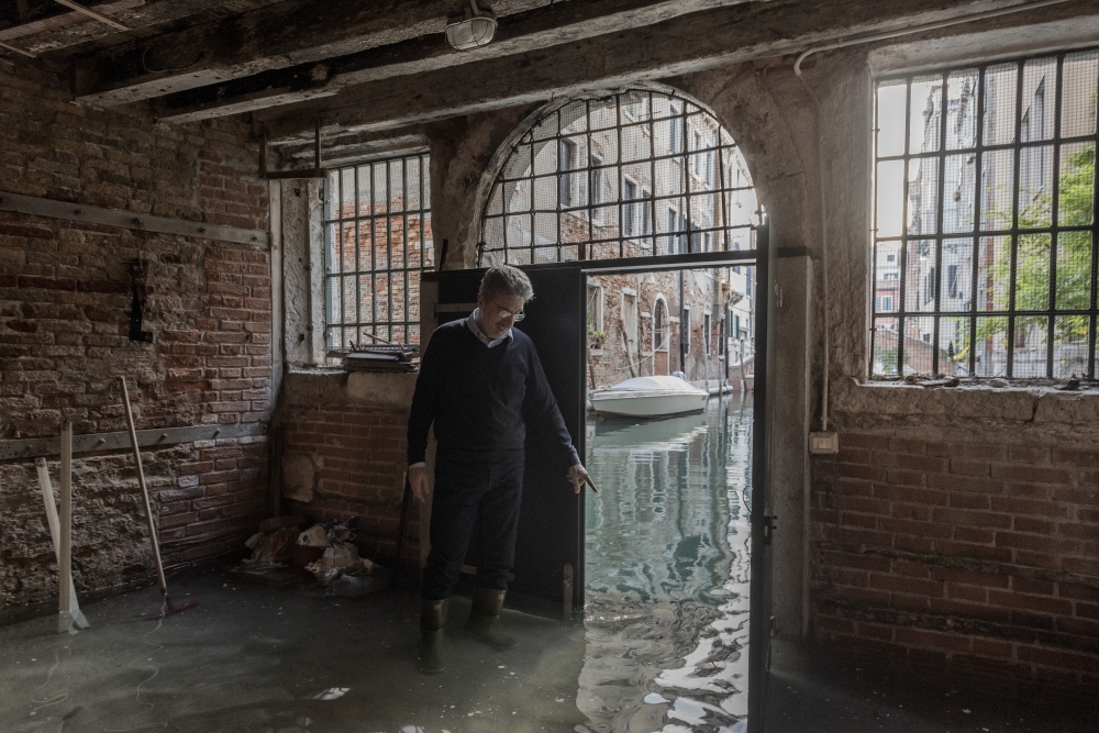 Alvise Papa stands in floodwater in the basement of his home, which remains vulnerable to floods, in Venice, Italy on Nov. 19, 2022. (Laetitia Vancon/The New York Times)