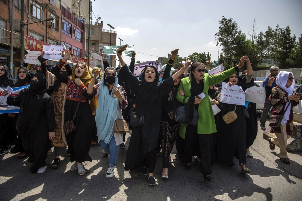 Women protest in Kabul before Taliban fighters fire into the air, sending them fleeing, Aug. 13, 2022. (Kiana Hayeri/The New York Times)