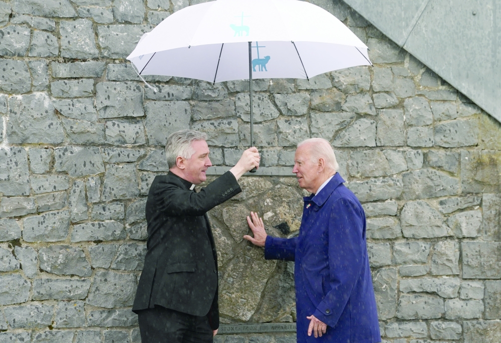 US President Joe Biden touches the original gable wall of the church at the Knock Shrine, with father Richard Gibbons, in County Mayo, Ireland. - Reuters

