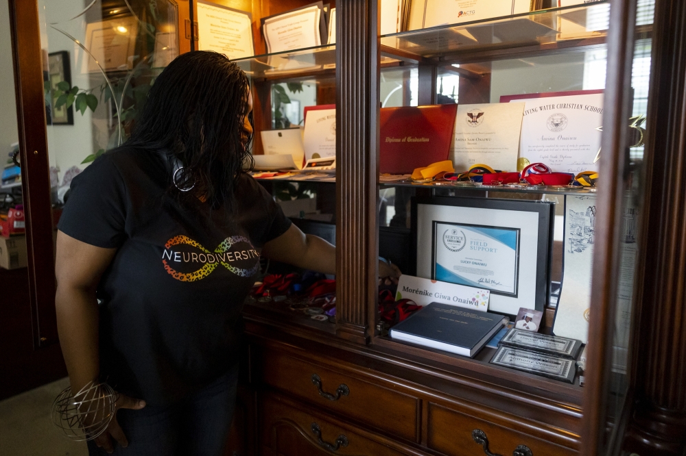 Morenike Giwa Onaiwu with a bound copy of her Ph.D. thesis, “Bringing Fire to the People: Activist Scholarship, Creative Collaboration, and International Advocacy Through the Lens of Black Disability Studies,” alongside other accolates and awards earned by her children in Houston, April 6, 2023. (Annie Mulligan/The New York Times)