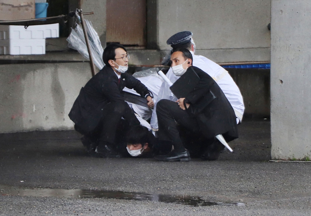 A man (bottom) is arrested after throwing what appeared to be a smoke bomb in Wakayama on April 15, 2023. Japanese Prime Minister Fumio Kishida was evacuated from a port in Wakayama after a blast was heard, but he was unharmed in the incident, local media reported on April 15. - Japan OUT
 (Photo by JIJI PRESS / AFP)

