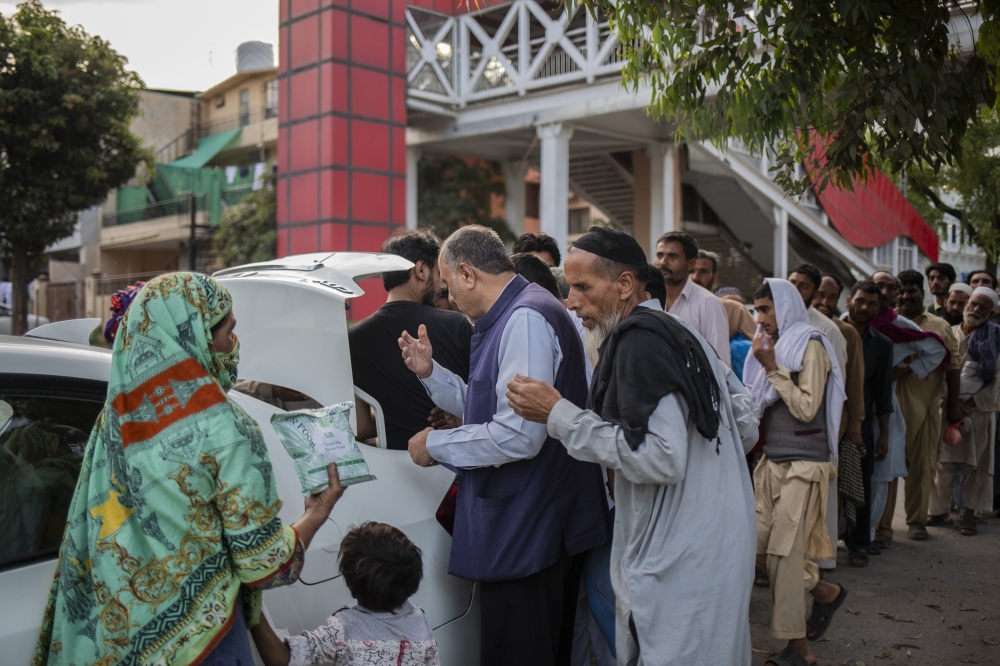 A local resident distributed ration essentials such as wheat and sugar to those in need in Islamabad, Pakistan, on April 15, 2023. (Saiyna Bashir/The New York Times)
