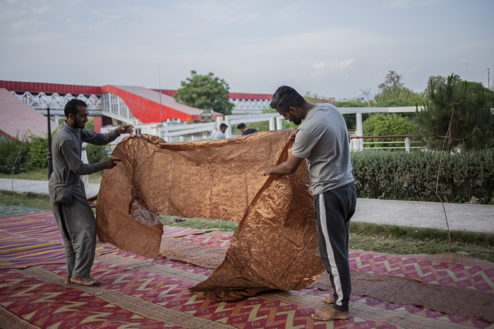 Volunteers prepare a tablecloth to serve food for people to break their fast during the Muslim holy month of Ramadan in Islamabad, Pakistan, on April 15, 2023. (Saiyna Bashir/The New York Times)