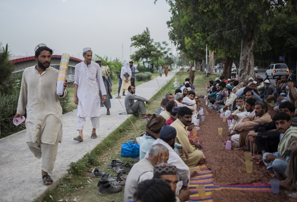 People wait to break the fast with the help of volunteers during the Muslim holy month of Ramadan in Islamabad, Pakistan, on April 15, 2023. (Saiyna Bashir/The New York Times)
