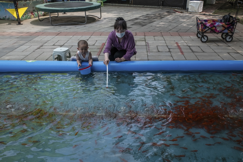 A woman with a child at a park in Beijing, on June 12, 2022. (Gilles Sabrié/The New York Times)