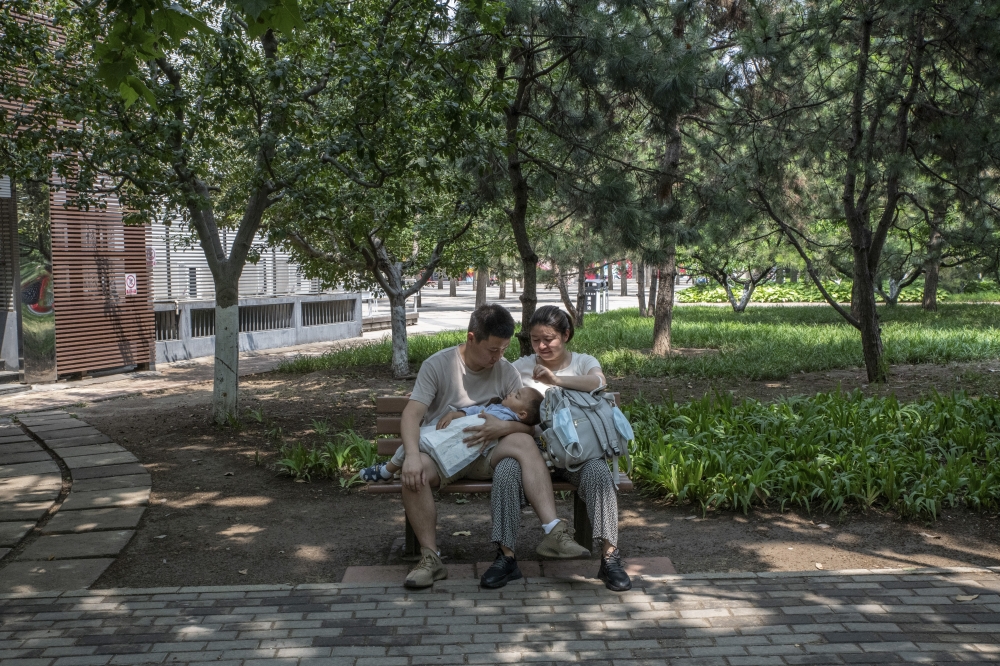 A couple with a baby in a park in Beijing, on June 12, 2022. (Gilles Sabrié/The New York Times)