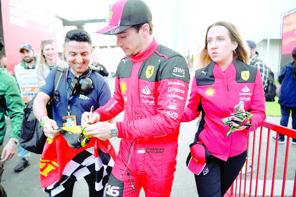 Ferrari's Monegasque driver Charles Leclerc signs autographs to fans after the qualifying session for the Formula One Azerbaijan Grand Prix at the Baku City Circuit in Baku on April 28, 2023. (Photo by NATALIA KOLESNIKOVA / AFP)

