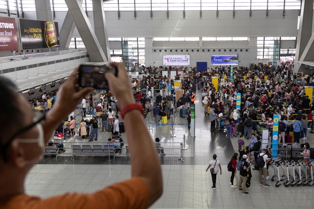 A man takes a picture of passengers queueing at the Ninoy Aquino International Airport, in Pasay City, Metro Manila, Philippines