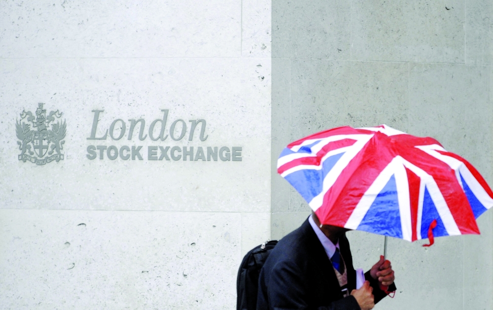 A worker shelters from the rain as he passes the London Stock Exchange in London