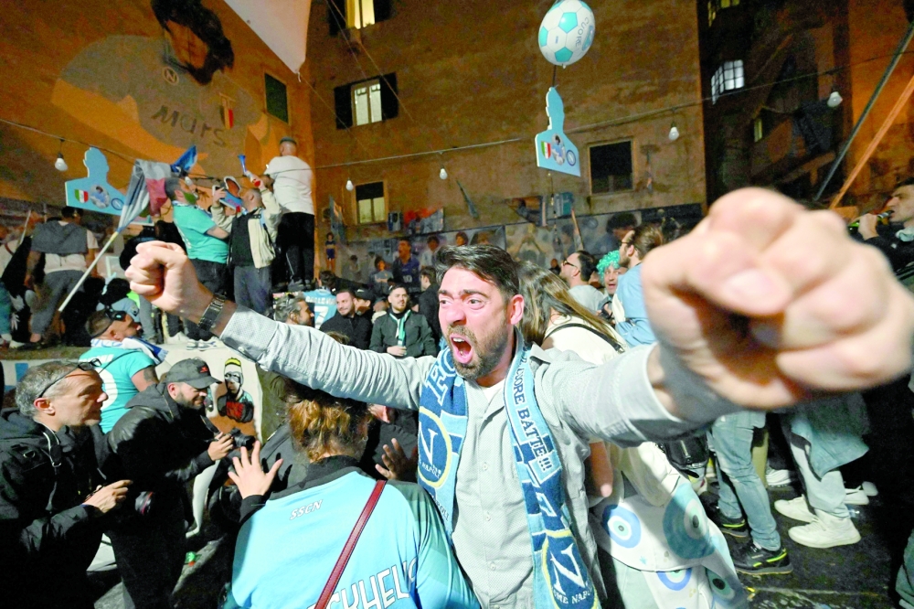 TOPSHOT - Fans of SSC Napoli gathering at the Largo Maradona in the Quartieri Spagnoli district on May 4, 2023 in Naples to watch a live broadcast of a potentially decisive match between Udinese and Napoli played in Udine, react after Napoli scored an equalizer, anticipating the celebration of the club's Italian champions "Scudetto" title, as Napoli is to play a potentially decisive match in Udine. Napoli has been waiting 33 years to be named Italian champions, and a potentially decisive game on May 4 against Udinese in Udine may secure the title. (Photo by Alberto PIZZOLI / AFP)

