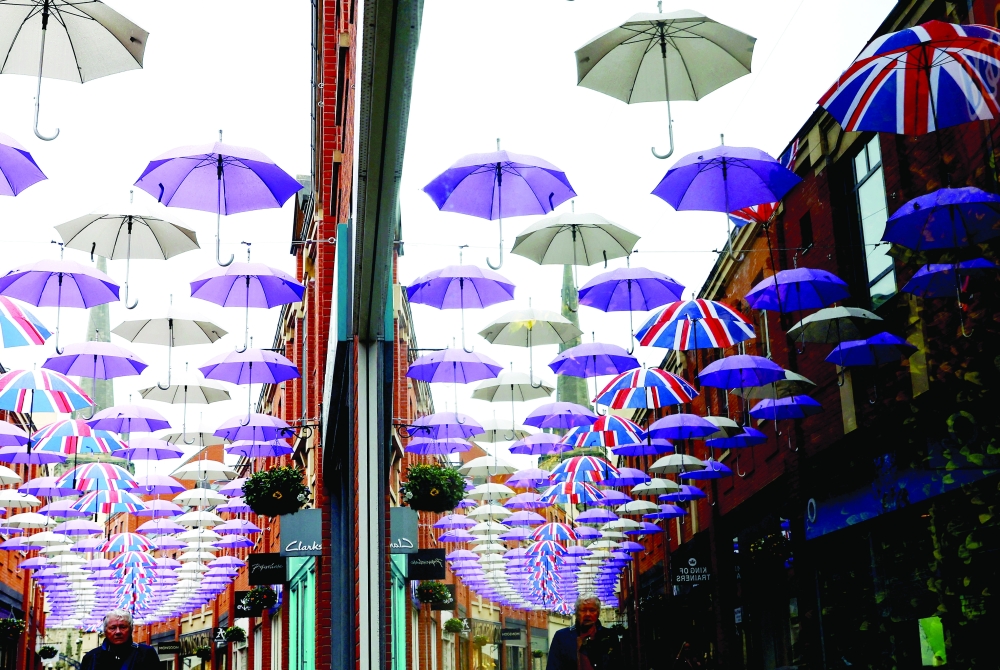A man walks under a display of umbrellas in Durham, Britain. - Reuters