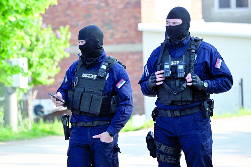 Masked policemen secure an area in the village of Dubona near the town of Mladenovac, about 60 kilometres south of Serbia’s capital Belgrade, in the aftermath of a drive-by shooting. — AFP