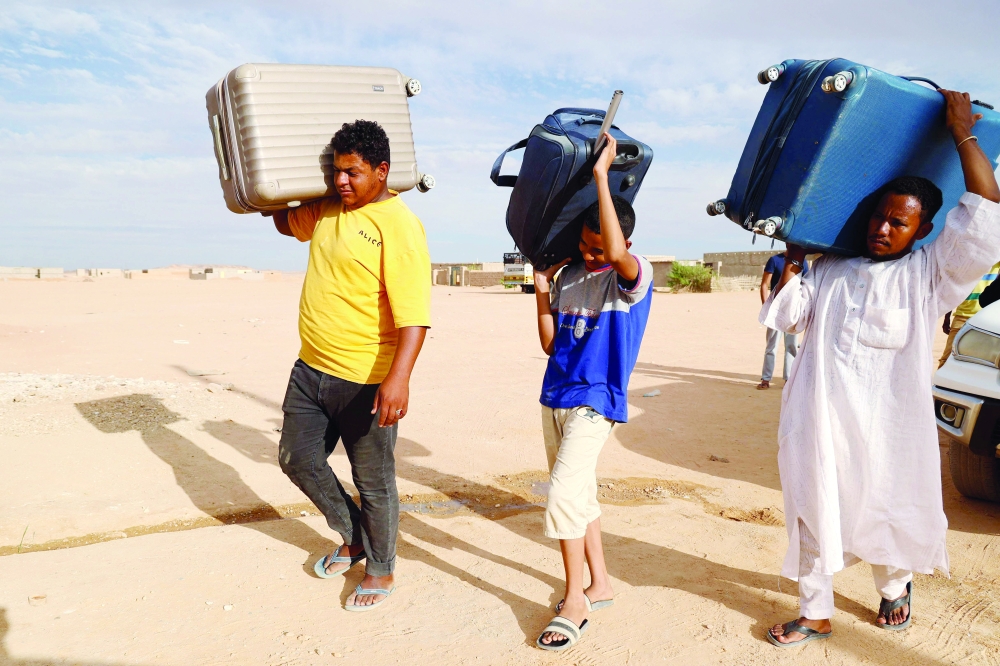 People carry suitcases in the Sudanese town of Wadi Halfa bordering Egypt. In three weeks of fighting, thousands have rushed to escape, often only having had the time to grab their most basic essentials. — AFP