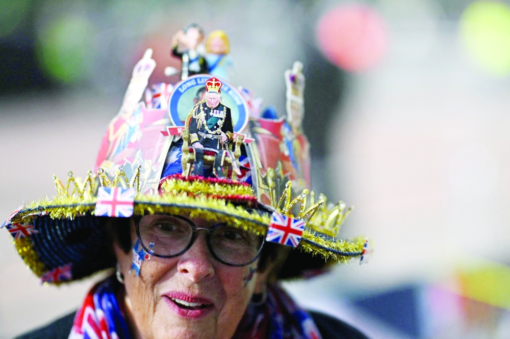 A Royal fan wears an elaborate hat in honour of Britain's King Charles III, near to Buckingham Palace in central London ahead of the coronation weekend. - AFP