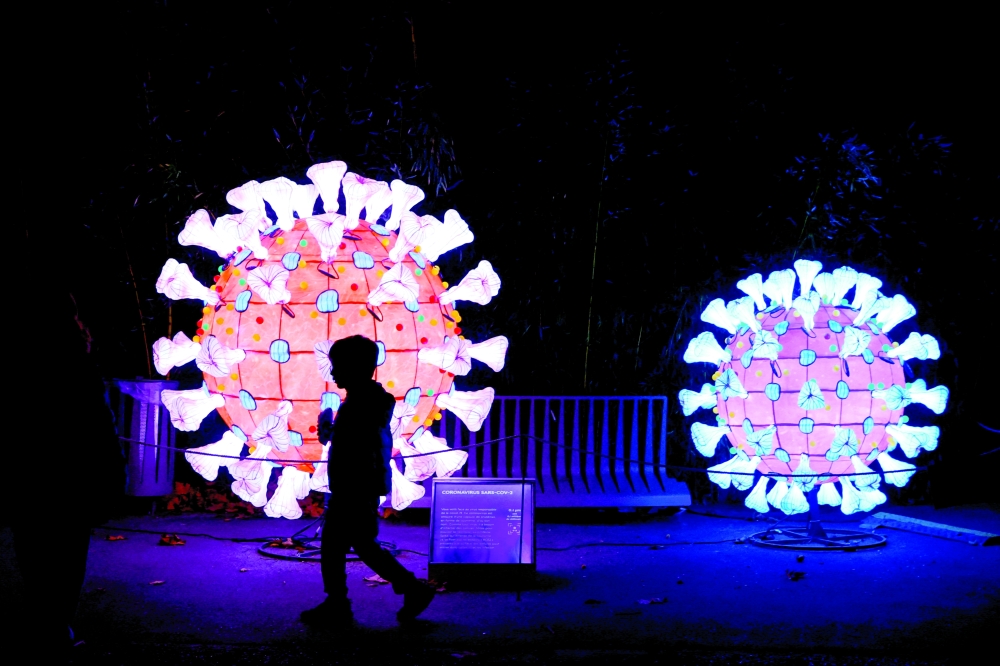 A visitor walks past an illuminated coronavirus model as he visits the 'Mini-Worlds on the Way of Illumination' exhibition during the Light Festival preview at the Botanical garden in Paris. - Reuters File 