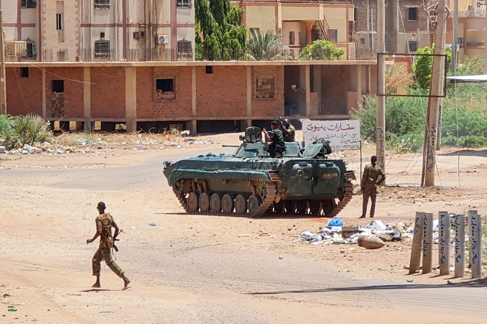 Sudanese Army sodliers walk near tanks stationed on a street in southern Khartoum, on May 6, 2023, amid ongoing fighting against the paramilitary Rapid Support Forces. Air strikes battered Sudan's capital on May 6, as fighting entered a fourth week only hours before the warring parties are to meet in Saudi Arabia for their first direct talks. (Photo by AFP)

