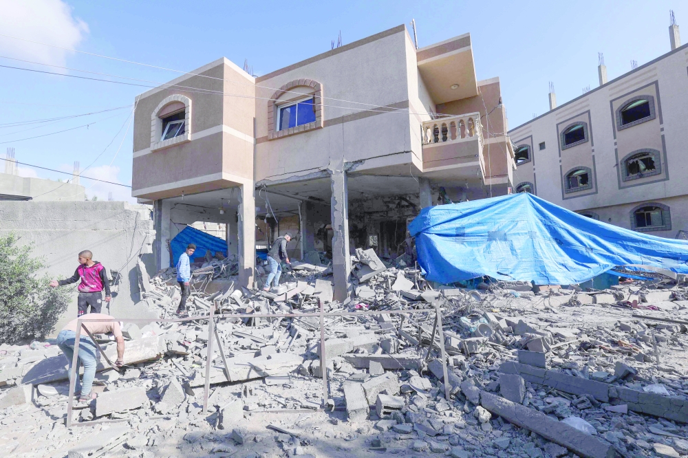 Palestinian men inspect the heavily-damaged house of  Jihad Ghannam killed in Israeli air strike, in Gaza. — AFP 