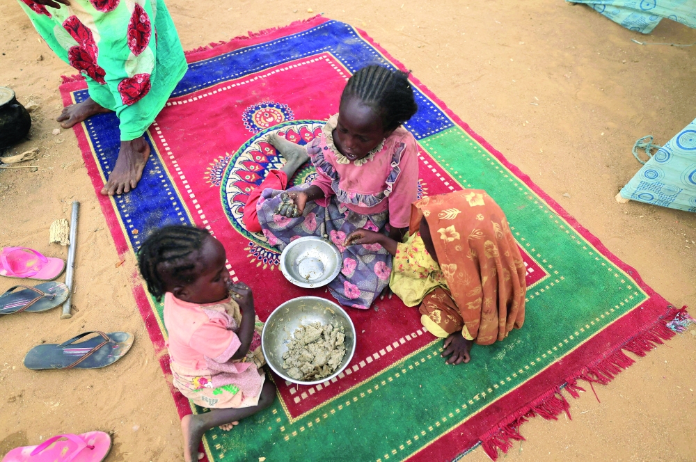 Sudanese refugee children who have fled the violence in Sudan's Darfur region eat their breakfast  beside makeshift shelters near the border between Sudan and Chad in Koufroun, Chad - Reuters