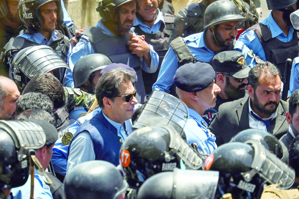 Policemen escort Pakistan's former Prime Minister Imran Khan as he arrives at the high court in Islamabad. - AFP 
