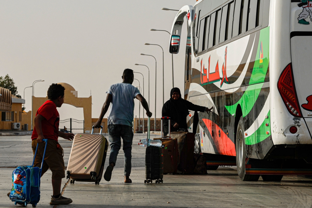 Passengers fleeing war-torn Sudan cross into Egypt through the Argeen Land Port on May 12, 2023. (Photo by Khaled DESOUKI / AFP)


