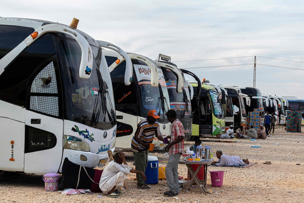 Sudanese drivers rest by their buses after transporting evacuees from Sudan into Egypt, in Wadi Karkar village near Aswan on May 14, 2023. 