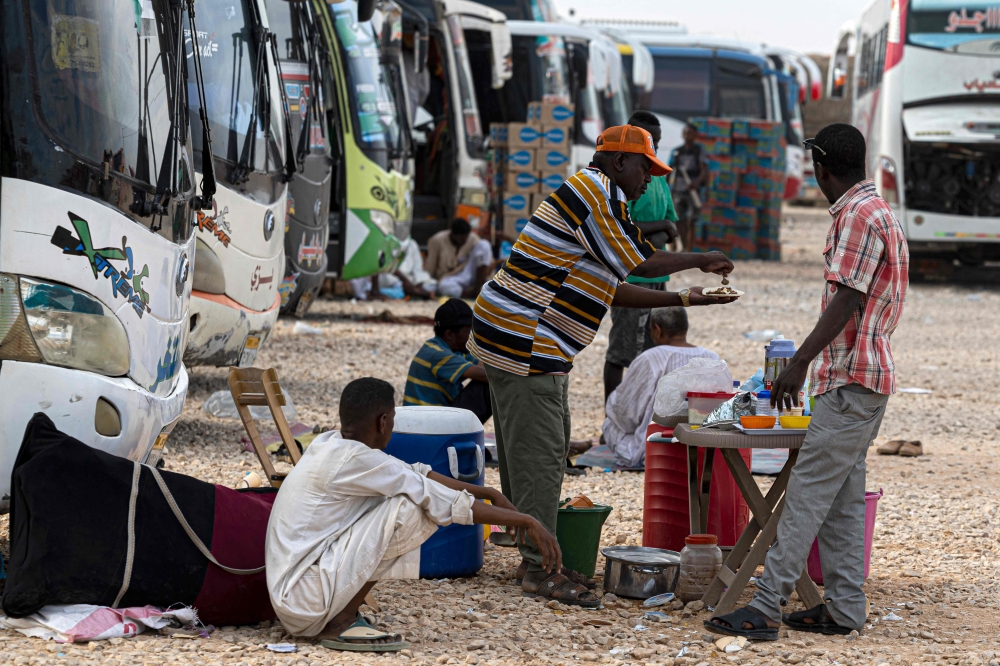 Sudanese drivers rest by their buses after transporting evacuees from Sudan into Egypt, in Wadi Karkar village near Aswan on May 14, 2023. O