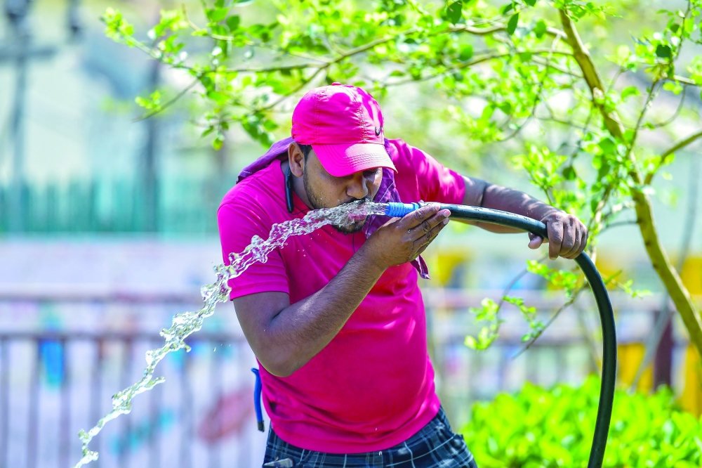 A man drinks water from a running pipe during a hot summer afternoon in Prayagraj, India, on Monday. - AFP