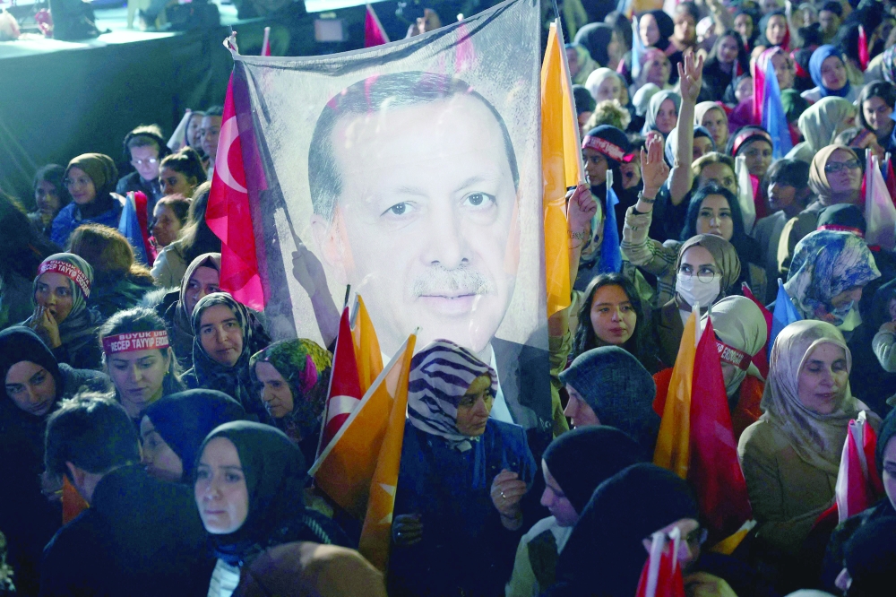 Supporters of President Erdogan holds a flag of his portrait outside the AK Party headquarters after polls closed in Ankara. — AFP 