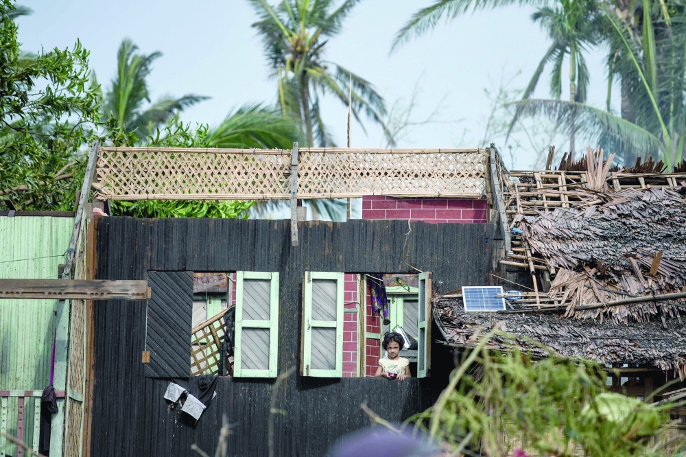 A girl looks outside a window from her destroyed house after Cyclone Mocha hit in Sittwe. — AFP