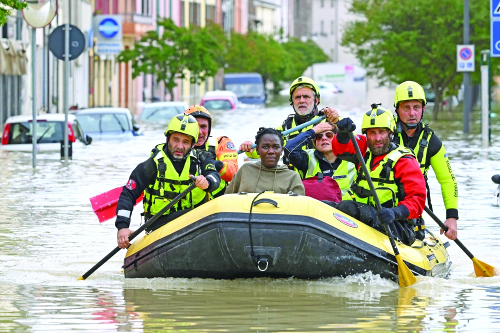 Rescuers transport a resident in a dinghy across a flooded street in the town of Lugo after heavy rains caused flooding across Italy's northern Emilia Romagna region, killing five people. - AFP


