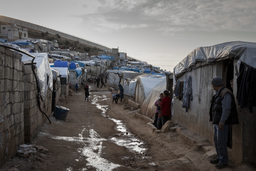 Displaced families at the Al-Nasr camp near Turkey's border wall, rear, in Syria, March 4, 2020. (Ivor Prickett/The New York Times) 